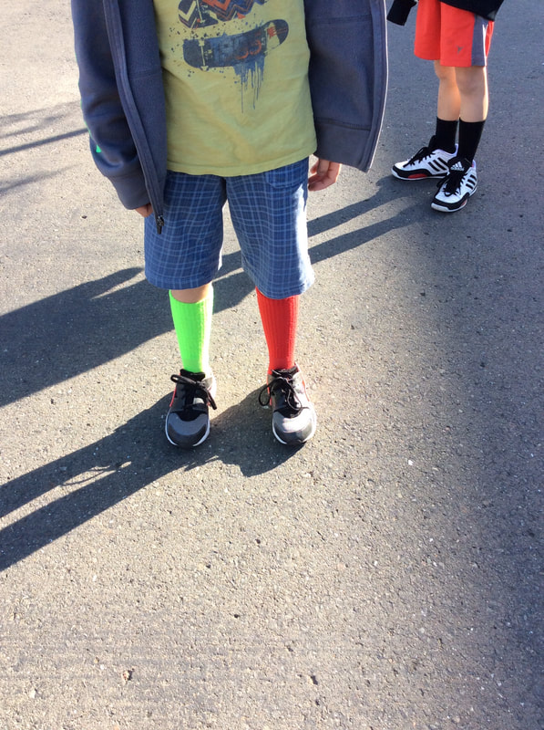 A young boys legs wearing one red sock and one green sock